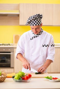 Young professional cook preparing salad at kitchen