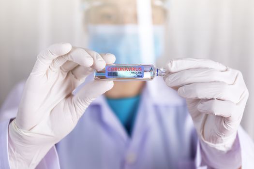 Covid-19 coronavirus vaccine. Close up hands of scientist show Covid-19 vaccine in glass vial. Hands of doctor wear latex glove holding Covid-19 vaccine in glass vial. Healthcare and medical concept.
