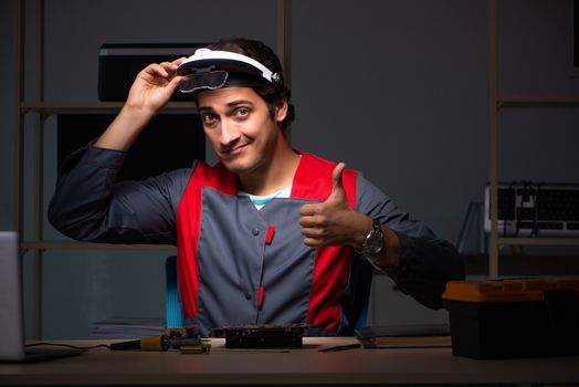 Young handsome repairman repairing computer 