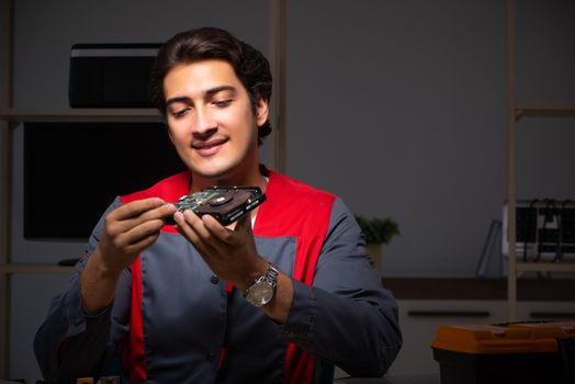 Young handsome repairman repairing computer 