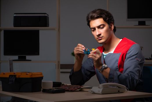 Young handsome repairman repairing computer 