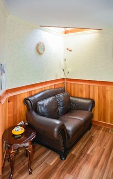 Luxury brown leather loveseat in room corner under the sunroof