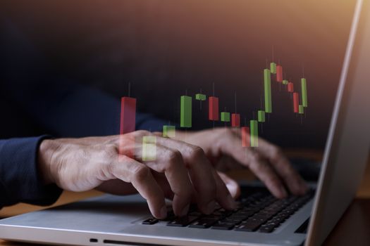 Business and technology concept  Close up businessman hands with laptop and candlestick chart background. Businessman hands use computer network control trade buy and sell stock market