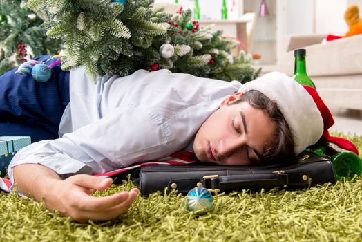 Young handsome employee celebrating Christmas at workplace 