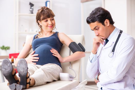 Young doctor checking pregnant woman's blood pressure