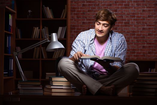Young handsome student preparing for exams at night 