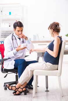 Young doctor checking pregnant woman's blood pressure