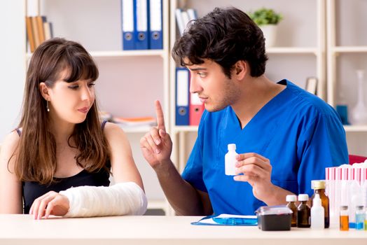 Young woman with bandaged arm visiting male doctor traumotologist 