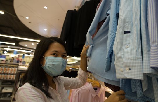 A woman shopping in a mall wearing a protective mask to prevent the coronavirus.