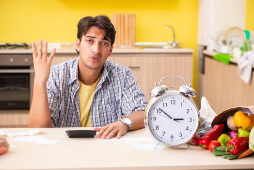 Young man calculating expences for vegetables in kitchen 
