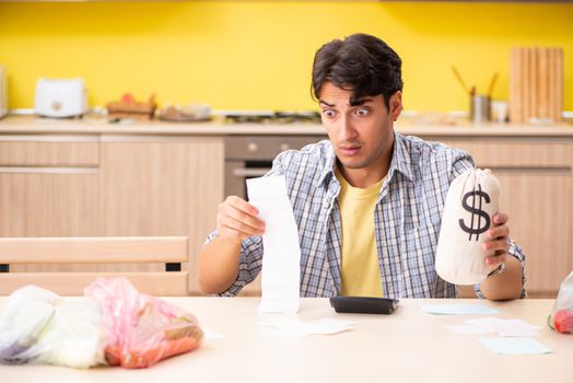 Young man calculating expences for vegetables in kitchen 