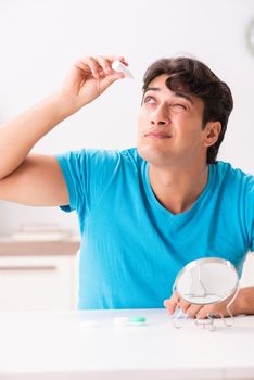 Man trying contact lenses at home