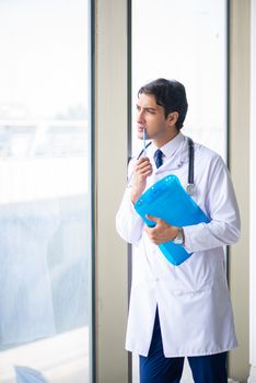Young handsome doctor standing at the window 