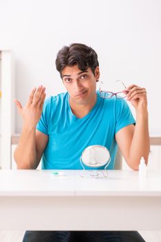 Man trying contact lenses at home