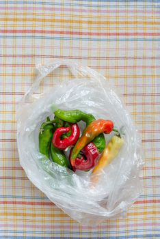 Hot red chili peppers in a translucide cellophane bag, put on an orange, red  and blue stripped napkin