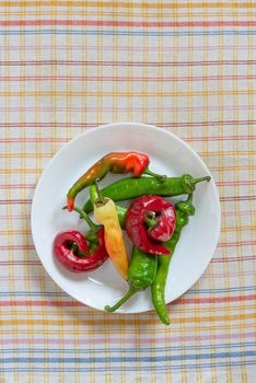 Hot red chili peppers in a white porcelain plate, put on an orange, red  and blue stripped napkin