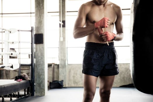 Boxer is swapping hands and punching bag at boxing ring.