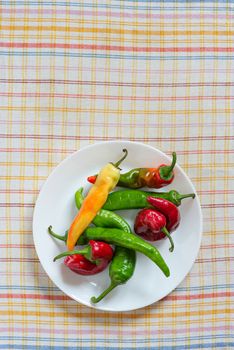 Hot red chili peppers in a white porcelain plate, put on an orange, red  and blue stripped napkin