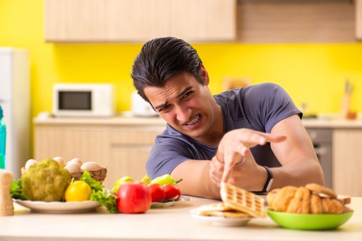 Man having hard choice between healthy and unhealthy food