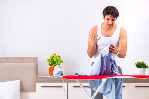 Young man ironing in the bedroom 