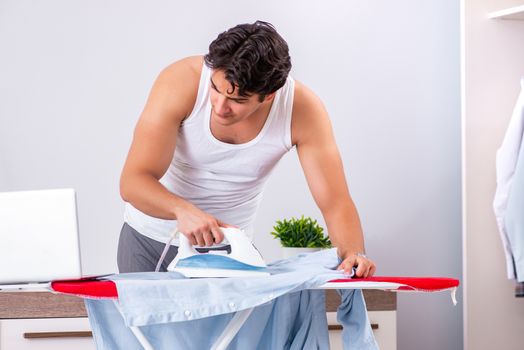 Young man freelancer ironing in the bedroom 