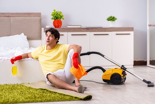 Young handsome man cleaning in the bedroom