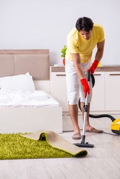 Young handsome man cleaning in the bedroom