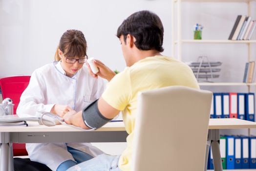 Young doctor checking patients blood pressure