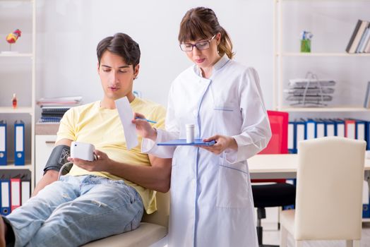 Young doctor checking patients blood pressure