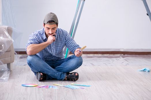 Young man contractor choosing color from rainbow 