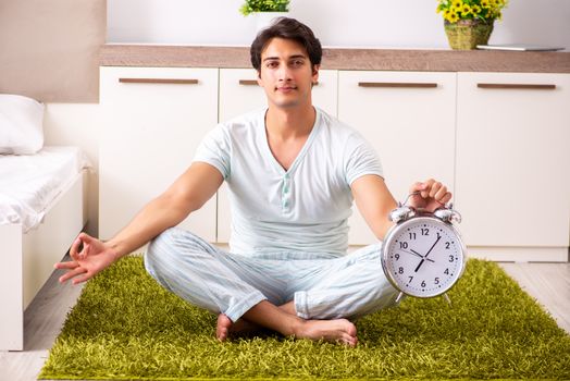 Young man doing yoga in bedroom in time management concept