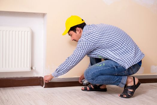 Young contractor sanding wall down with sandpaper 