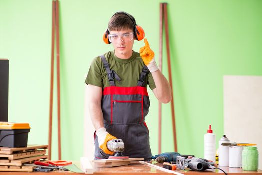 Young man carpenter working in workshop 