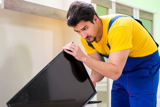 Male professional serviceman repairing tv at home