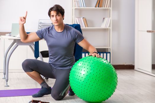 Young male employee exercising in the office