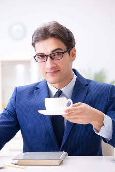 Young handsome businessman drinking coffee in the office 