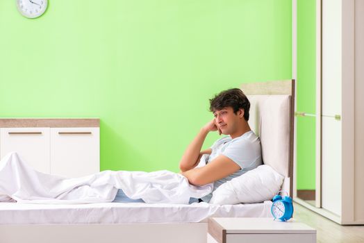 Young man having trouble waking up in early morning