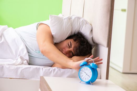 Young man having trouble waking up in early morning