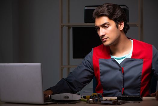 Young handsome repairman repairing computer 