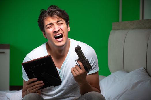 Young handsome man suffering from unrequited love in the bedroom 