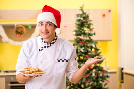 Young chef husband working in kitchen at Christmas eve 