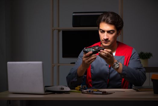 Young handsome repairman repairing computer 