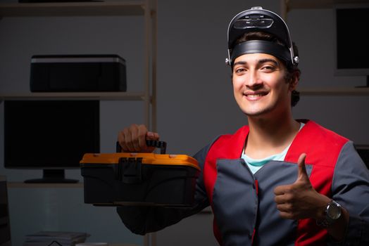 Young handsome repairman repairing computer 
