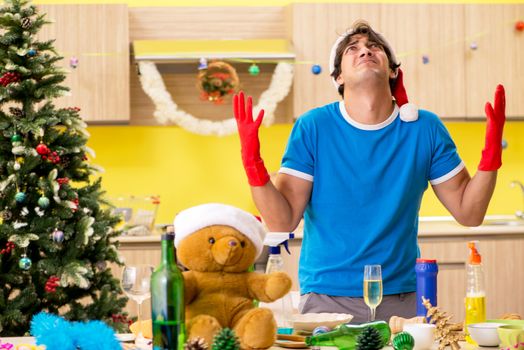 Young man cleaning kitchen after Christmas party 