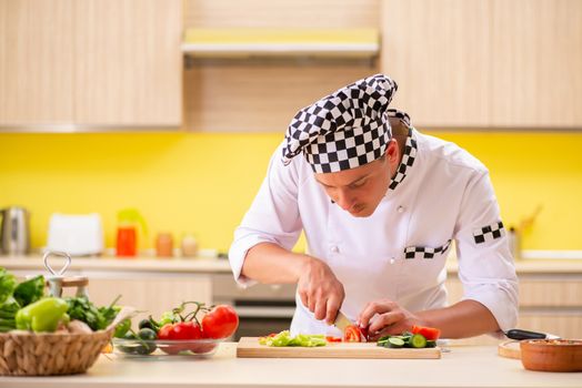 Young professional cook preparing salad at kitchen