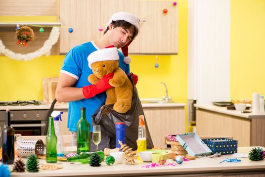 Young man cleaning kitchen after Christmas party 