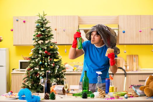 Young man cleaning kitchen after Christmas party 