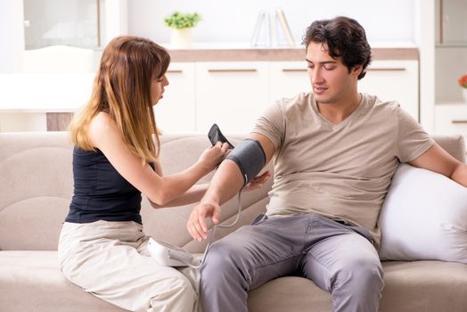 Wife checking husband's blood pressure  