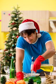 Young man cleaning kitchen after Christmas party 