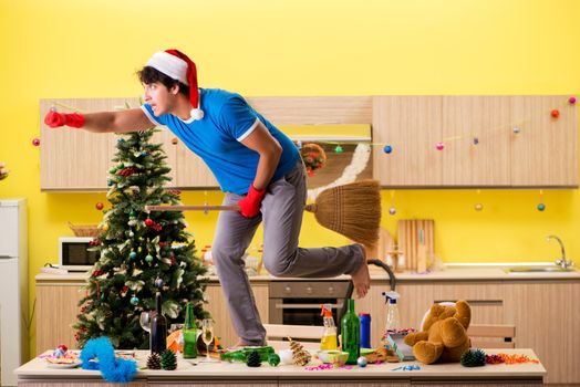 Young man cleaning kitchen after Christmas party 